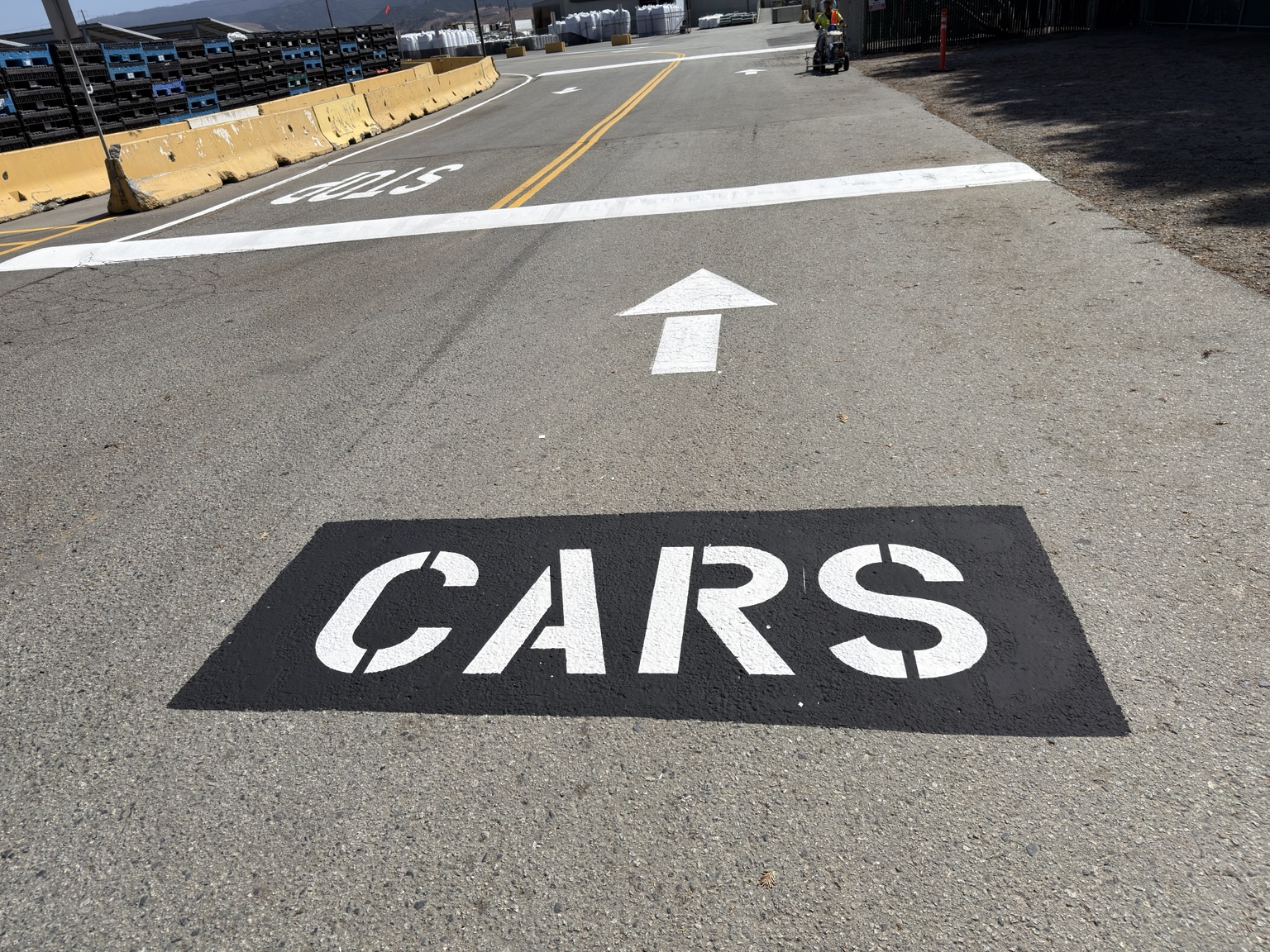 Industrial yard lane with a CARS stencil on a black patch and a white stop bar