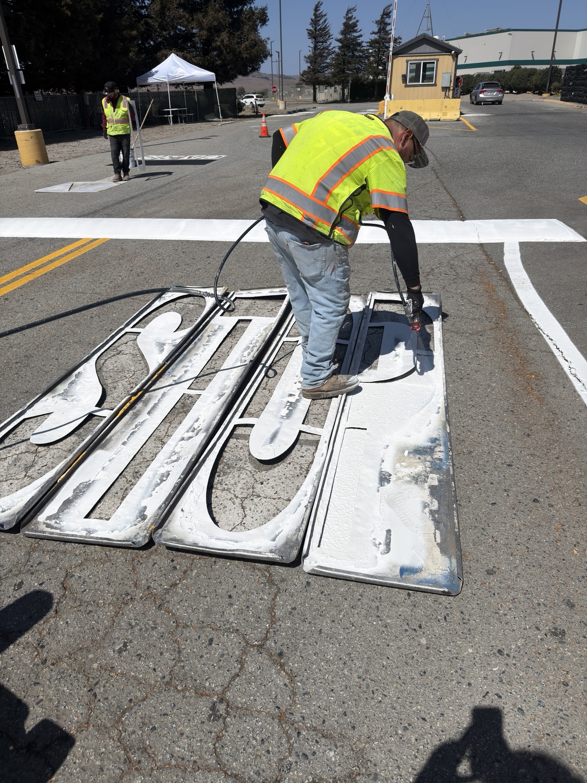 Crew member spraying a STOP stencil with a paint rig